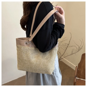Close-up of woven straw shoulder bag with khaki leather trim and silver metal hardware