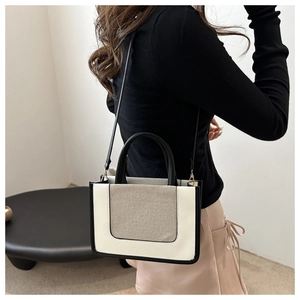 Detail of a black and beige contrast crossbody bag with woven texture panels