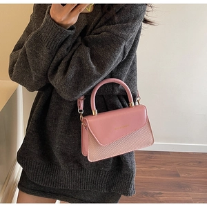 Detail of pink handwoven shoulder bag with faux leather flap and round handle
