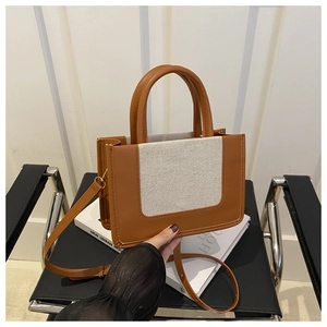 Close-up of vintage brown leather and beige canvas handbag with adjustable strap