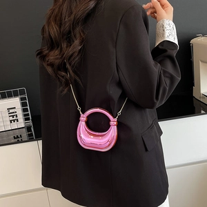 Glossy pink metallic half-moon mini bag with gold chain strap shown on a model