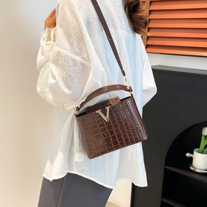 Brown crocodile pattern bucket bag with golden V-shaped buckle and crossbody leather strap