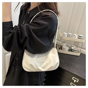 Detail of white pleated underarm bag with fashion logo on stylish faux leather texture