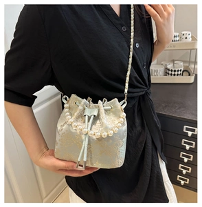 Detail of light green bucket bag with gold floral embroidery and premium pearl handle