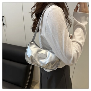 Detail of silver metallic underarm bag showing the oval fashion logo and wide shoulder strap