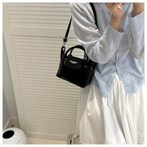 Detail of a black leather handbag featuring white fashion typography and silver hardware