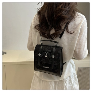 Detail of a black mini backpack with floral patterns, a bow, and heart pendant on a model