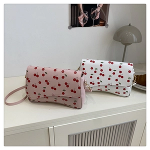 Detail of pink and white crossbody bags with cherry prints on a minimalist side table