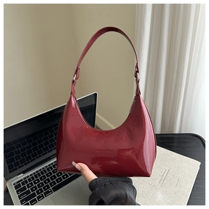 Dettaglio della borsa a mezzaluna in vernice rossa con finitura lucida e fibbia in metallo