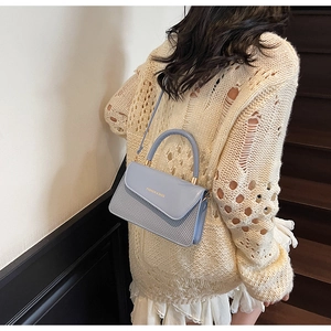 Detail of light blue shoulder bag with top handle and Fashion & Bags text on the flap