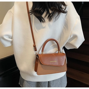 Detail view of brown woven PU leather crossbody bag with FASHION & BAGS logo on a model