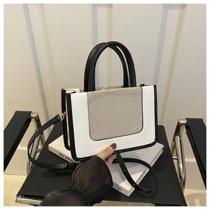 Three-color patchwork leather and canvas tote bag held by hand to show size and texture