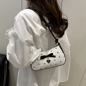 Sac baguette blanc chic avec jacquard à nœuds noirs et pendentif cœur sur modèle