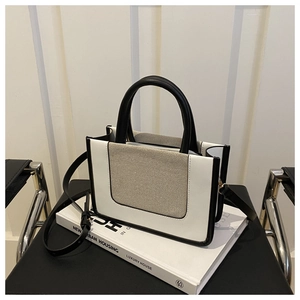 Detail of trendy color-block crossbody bag with leather handles on a chair