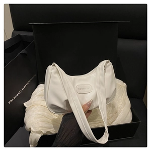 Detailed view of a white crescent shoulder bag inside a black gift box with tissue paper