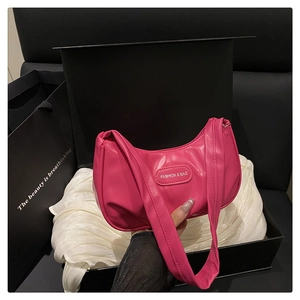 Detail of hot pink crescent bag with polished leather finish on silk cushion