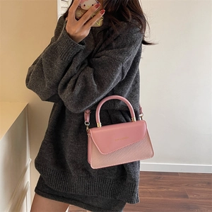 Pink minimalist crossbody bag with woven texture shown on a female model with sweater