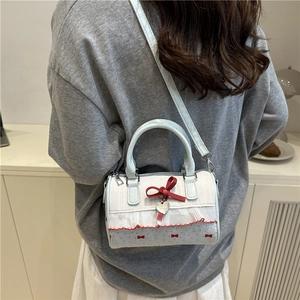 Sac Boston bleu clair à pois avec nœud rouge et pendentif cœur porté à l'épaule