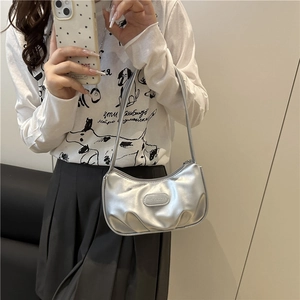 Silver metallic pleated crescent shoulder bag shown on a model for a trendy summer look