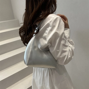 Moderna borsa hobo argento con forma a mezzaluna minimalista su scale bianche