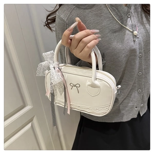 Detail of white matte leather bowling bag with bow metal buckle and lace trim