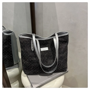 Détail du sac cabas à pois noirs avec des poignées en cuir argenté sur un tabouret
