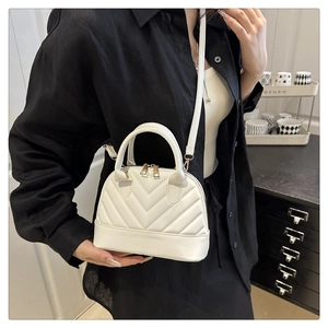 Detail of white V-quilted faux leather crossbody bag with elegant gold dual zipper closure