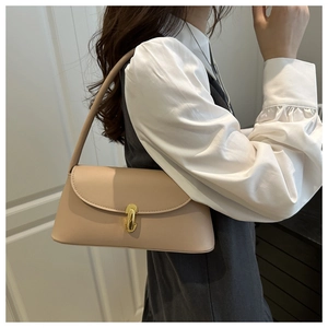 Detail of elegant beige baguette bag with golden U-shaped buckle on a female model