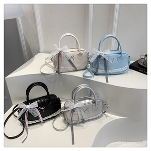 Detail of shell-shaped crossbody bags featuring lace trim and metal bow accents