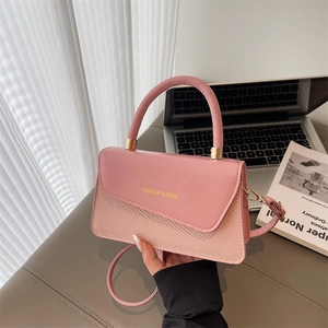 Detail of pink patchwork bag with woven texture, round handle, and gold hardware