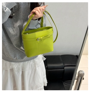 Minimalist lime green leather bucket bag with top handle and adjustable strap detail