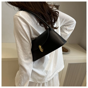 Detail of a black minimalist shoulder bag featuring a gold twist lock on a female model