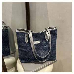 Détail du sac cabas en denim bleu à pois blancs avec finitions en cuir argenté élégant