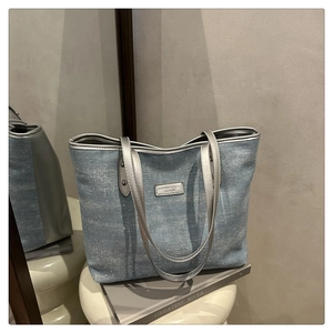 Gros plan sur un cabas en jean avec détails pailletés et plaque en métal argenté