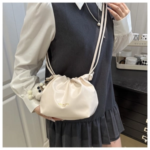 Detail of cream cloud bag with pleats, adjustable strap and cute plush bear charm