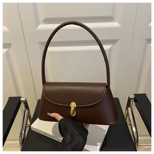Detail of brown vintage leather shoulder bag with gold clasp and elegant curved design