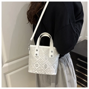 Detail of white jacquard crossbody bag with silver rivet accents and chic floral pattern