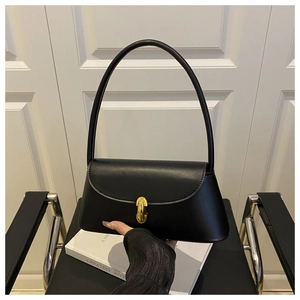 Detail of minimalist black leather crossbody bag with elegant gold metal twist lock