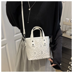 Detail of white leather bucket bag showing geometric texture and silver rivets
