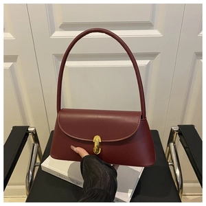 Detail of burgundy leather shoulder bag featuring a vintage gold-tone twist lock closure