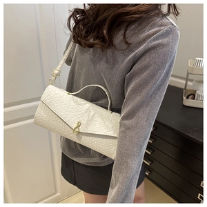 Détail de la texture tissée crème et de la boucle dorée du sac à bandoulière moderne