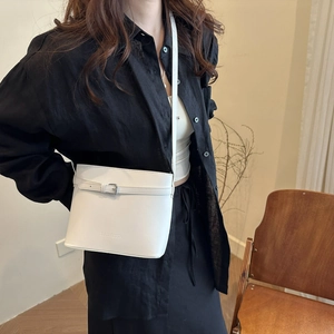 Chic white leather bucket bag for women worn by a model in a minimalist indoor setting