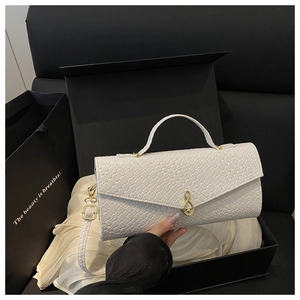 Détail d'un sac à main blanc tissé avec fermoir note de musique dorée dans sa boîte