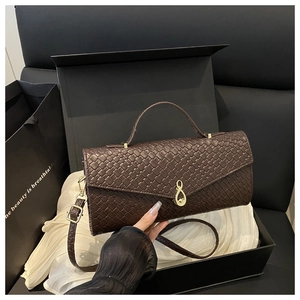 Détails d'un sac à main marron foncé au motif tressé avec boucle dorée et coffret cadeau en soie