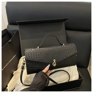 Détails de la texture tissée noire et du fermoir doré à l'infini sur le sac à main