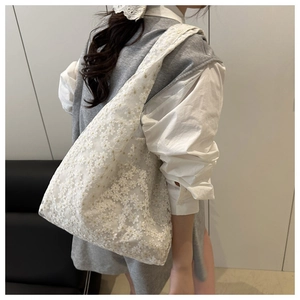 Detail of white lace flower embroidery on a breathable mesh shoulder tote bag