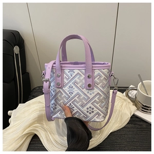 Detail of purple embroidery patterns and leather strap on a stylish crossbody square bag
