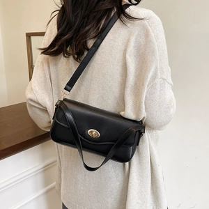 Minimalistische schwarze Leder-Baguette-Tasche mit Gold-Schnalle am Model