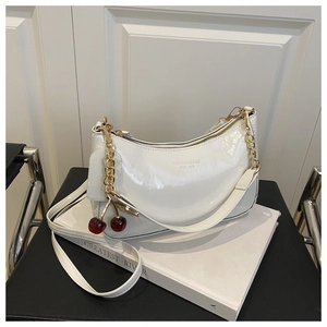 Sac à main en cuir verni blanc avec pendentif cerise et chaîne sur support blanc