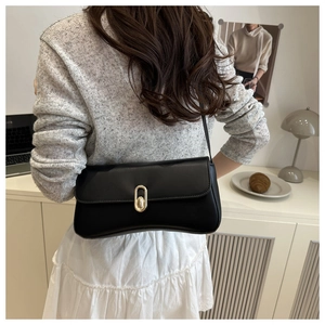 Sac baguette noir chic avec fermoir doré porté par un mannequin pour un style tendance